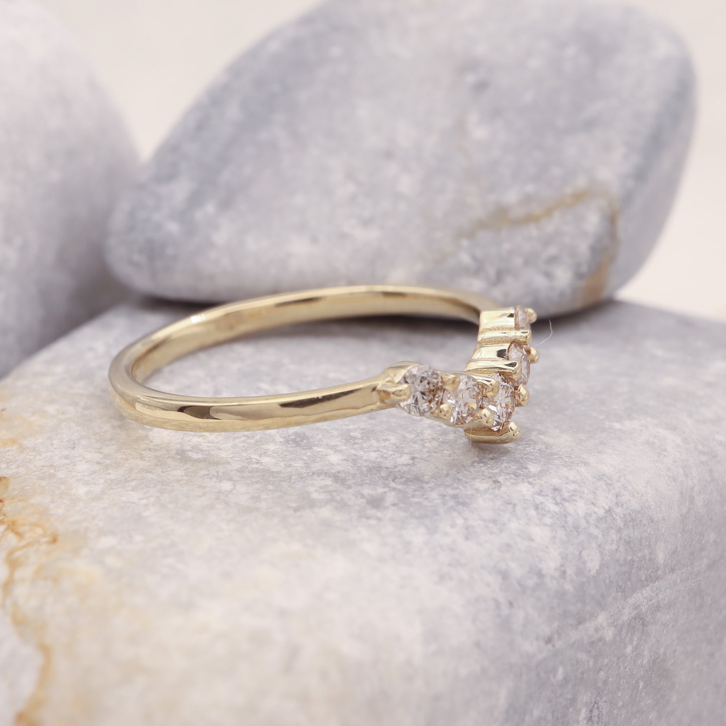 Side view of a curved wedding ring chevron style, featuring natural diamonds in a prong setting.