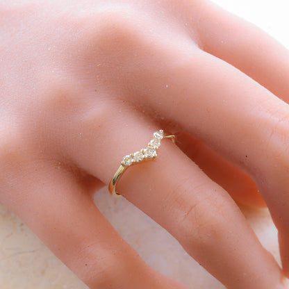 Curved diamond gold ring gracefully worn on a woman's finger, hand resting on a marble slab