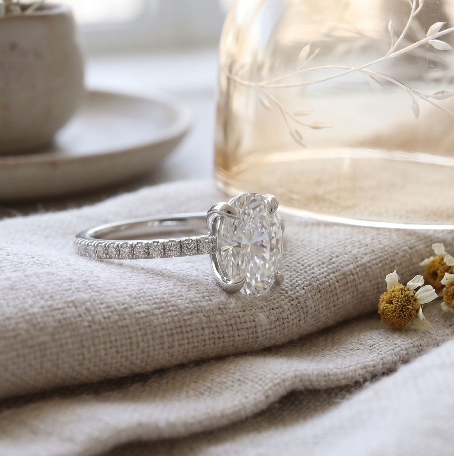 Angle view of oval diamond engagement ring in white gold and small diamonds.