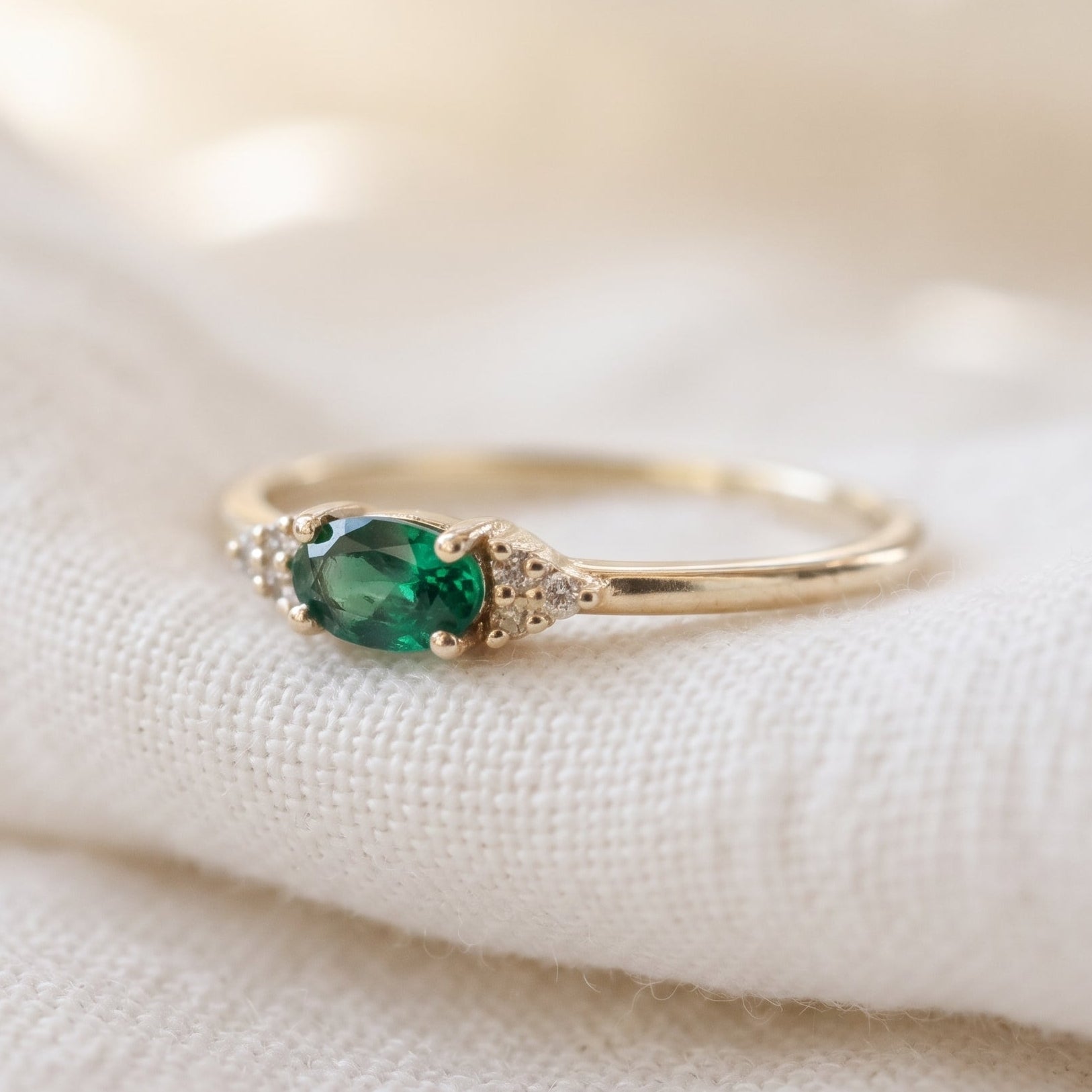 Minimalist emerald oval cut ring with 3 diamonds on each side in matte finish.