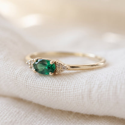 Minimalist emerald oval cut ring with 3 diamonds on each side in matte finish.