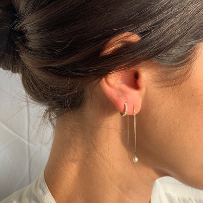 Elegant solid gold diamond huggie earring with a pave setting, paired with another Dina Jewelry Collection earring on a woman's ear