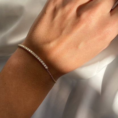 Woman's wrist adorned with the Half Diamond Bar Bracelet in Solid Gold, complemented by a Dina Jewelry ring on her finge