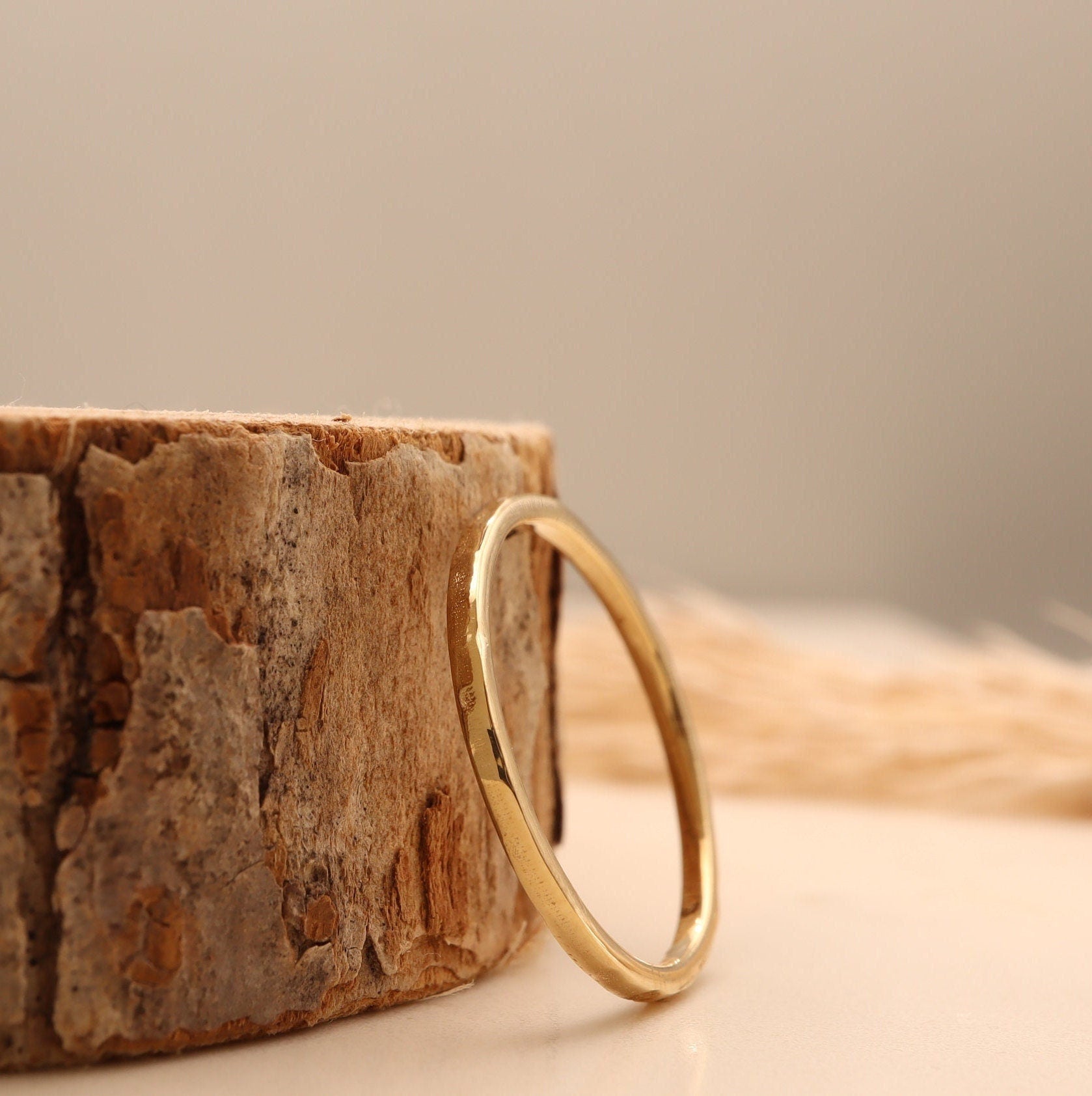 Hammered gold wedding ring resting against a wooden block