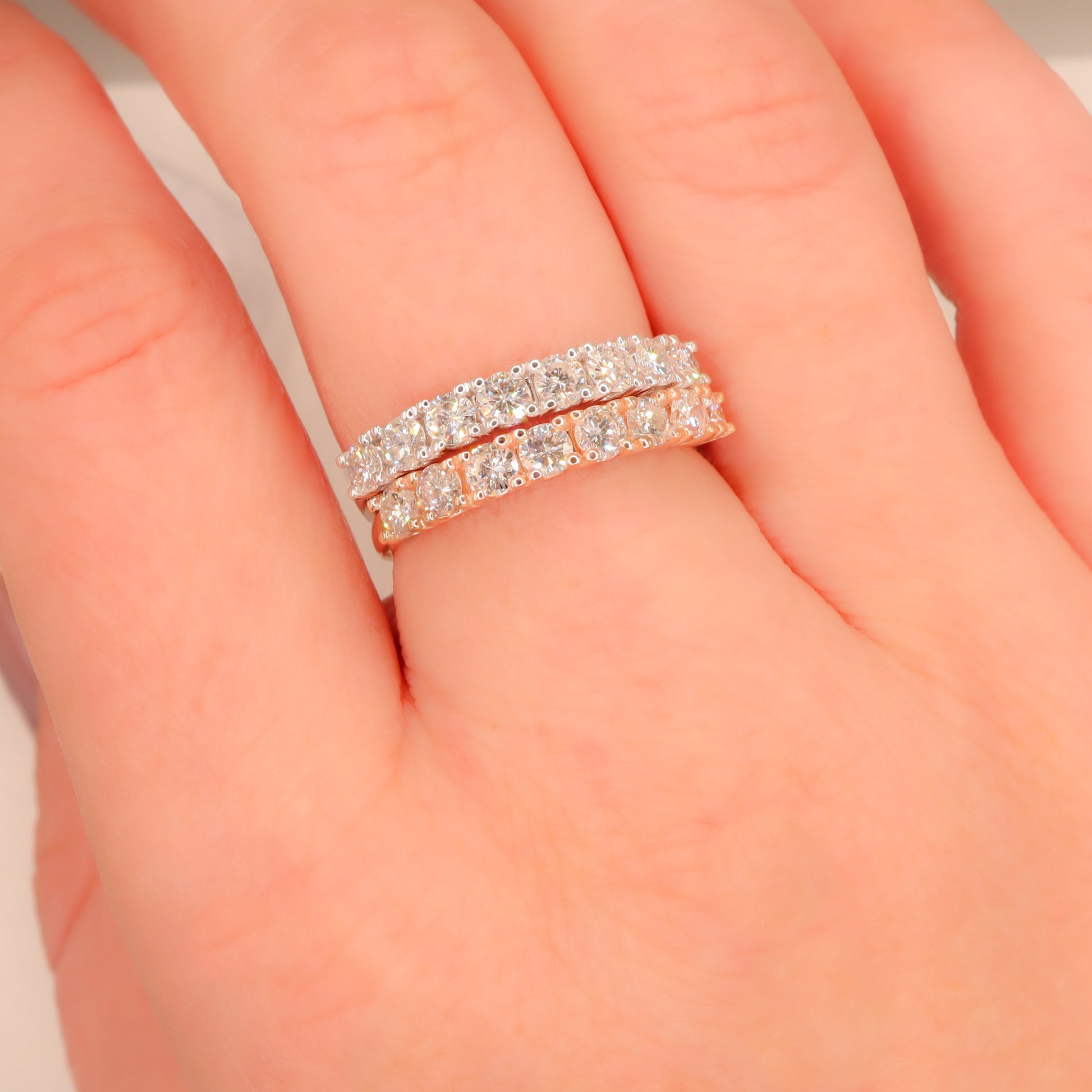 Graceful duo of Delicate Diamond Half Eternity Rings in rose and white gold, adorning a woman's finger.