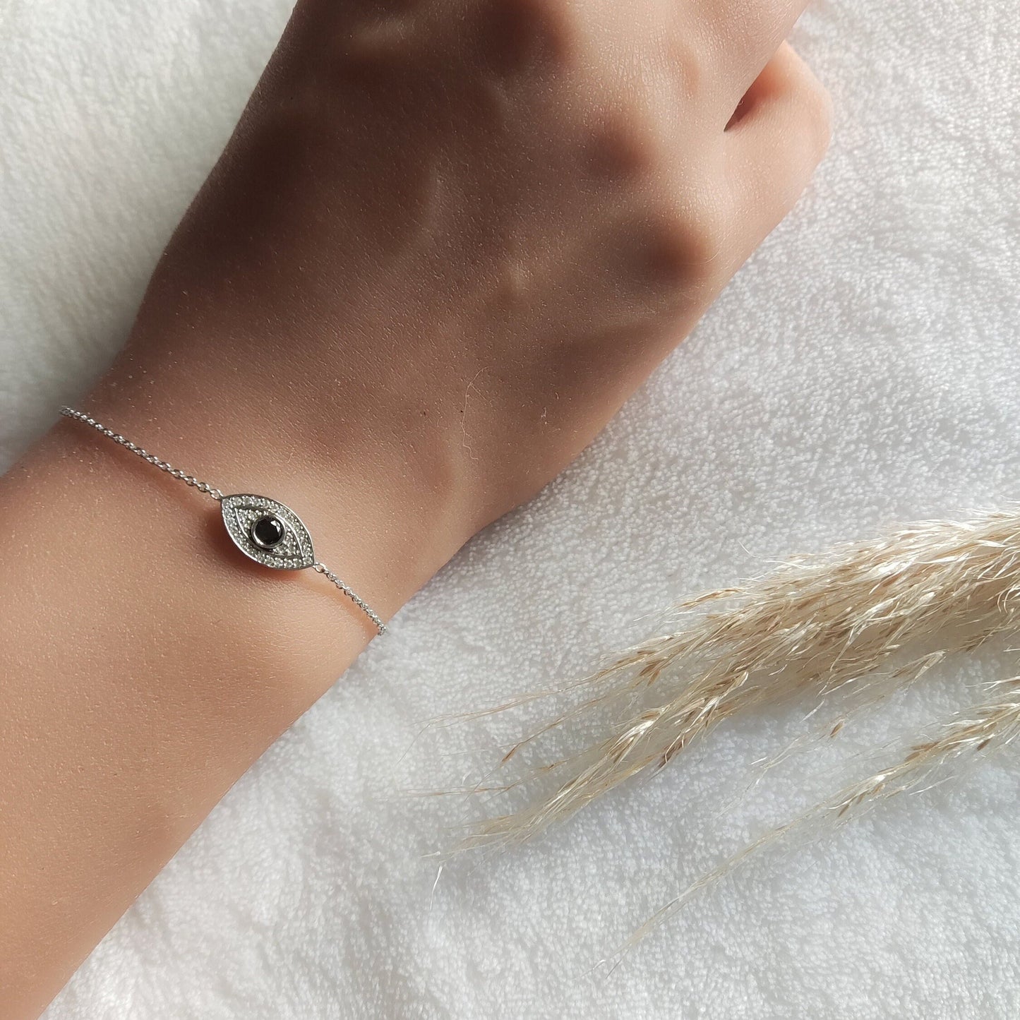 Elegant white gold Evil Eye Bracelet with Black & White Diamonds, gracefully worn on a woman's wrist.