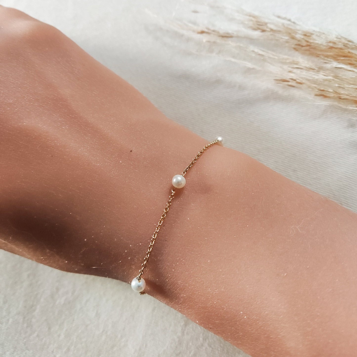 Pearl Station Bracelet with 3 pearls, made of solid gold, displayed on a  woman's wrist