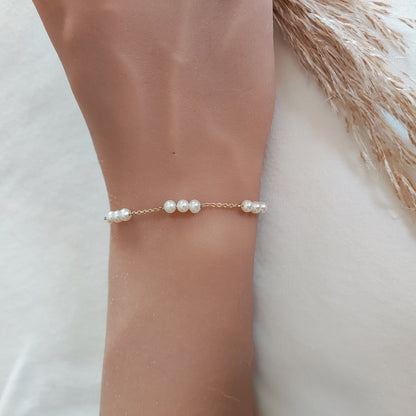 Stylish gold bracelet with Three Pearl Station design, worn on a female wrist.