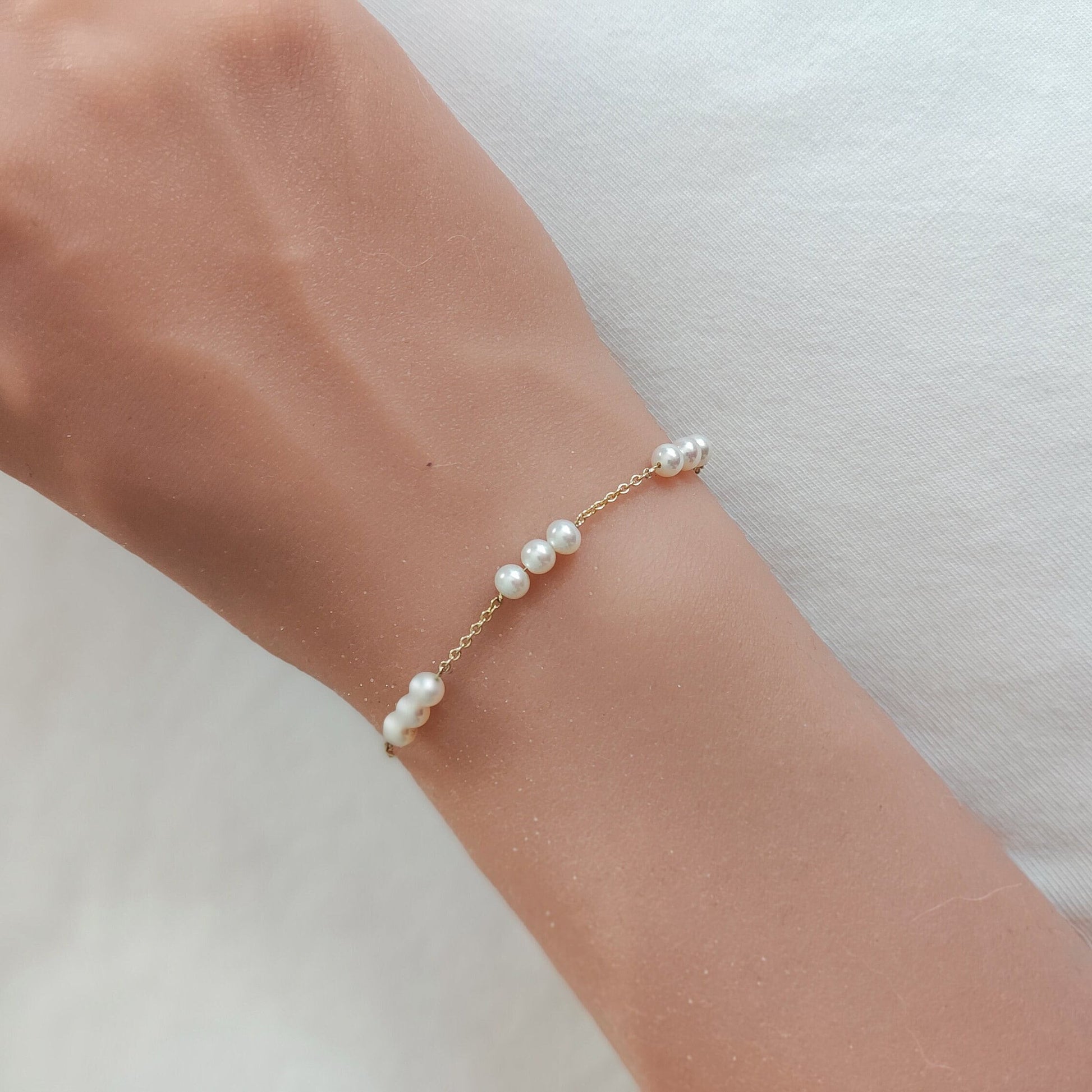 Elegant gold Three Pearl Station Bracelet adorning a woman's wrist.