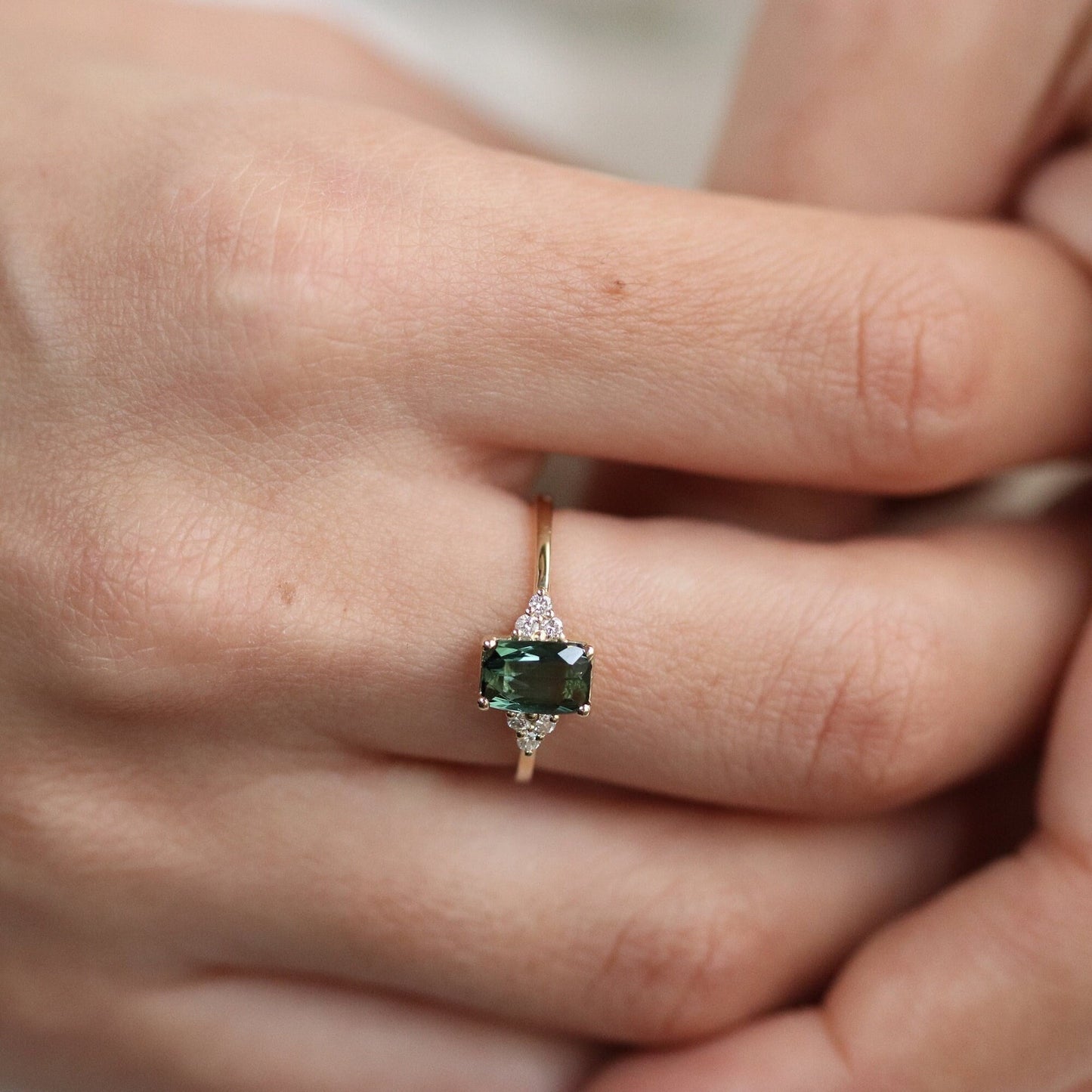 Green Tourmaline Emerald Cut Ring with Three Small Diamonds on Each Side elegantly worn on a woman's hand.