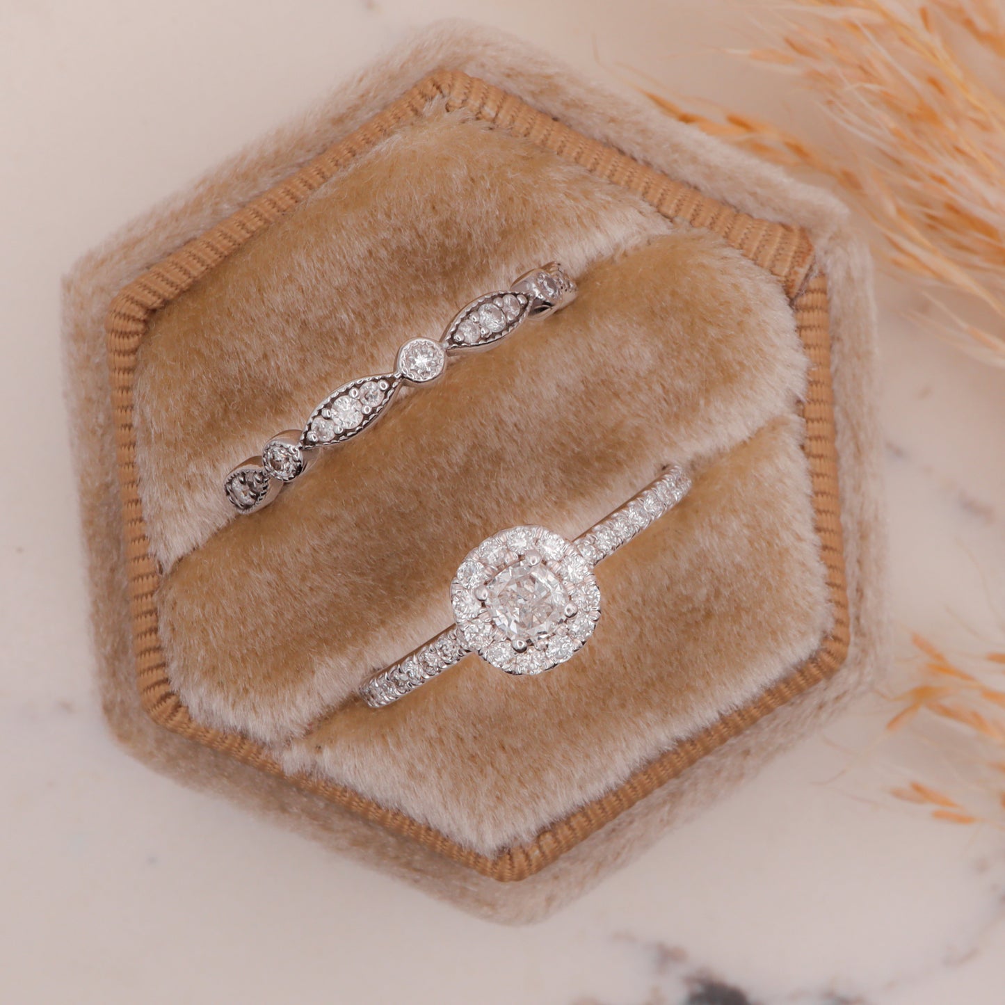 Eternity Band with Marquise & Round Diamonds in jewelry box beside halo diamond ring on marble slab.