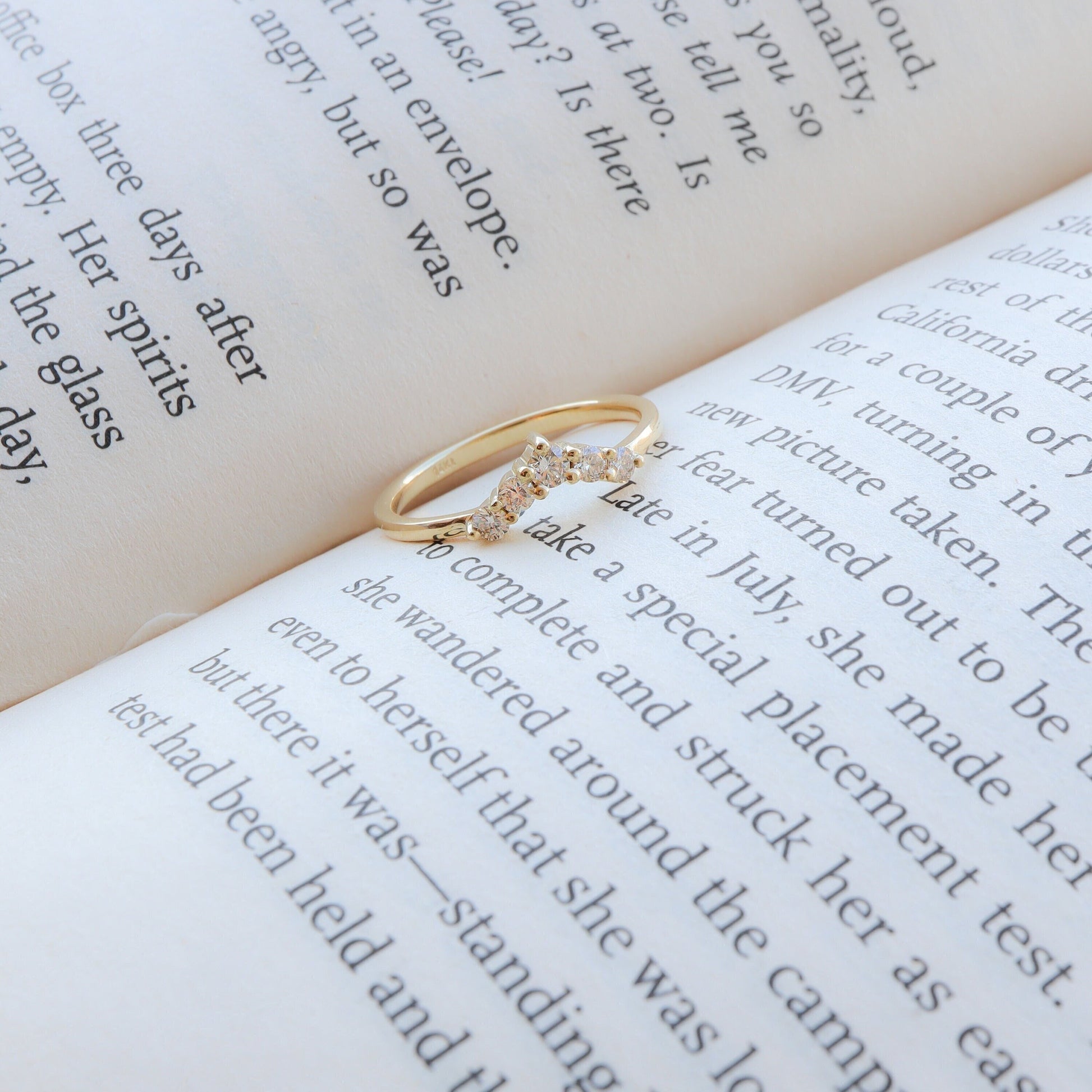 Curved diamond gold ring resting on an open book