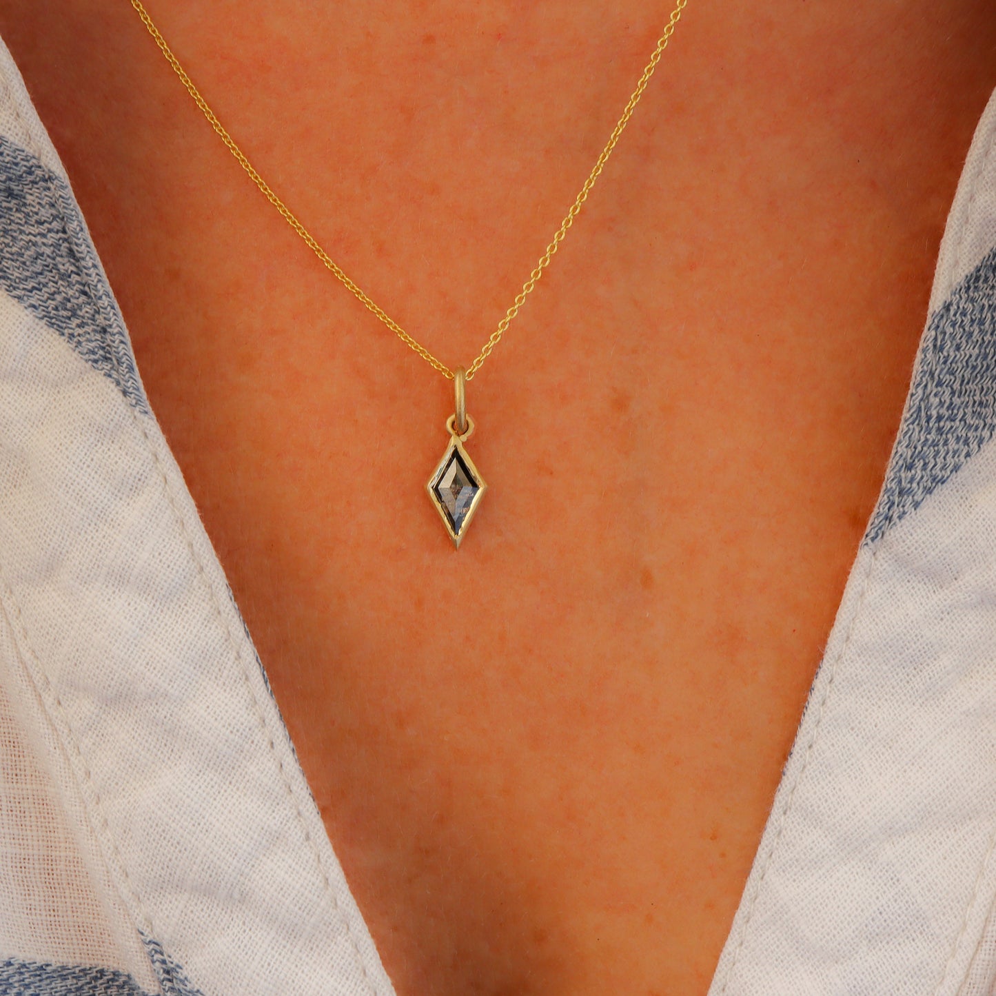 Salt and Pepper Diamond Gold Necklace in Kite Shape with Bezel Setting, adorning a woman's neck in a blue and white striped shirt.