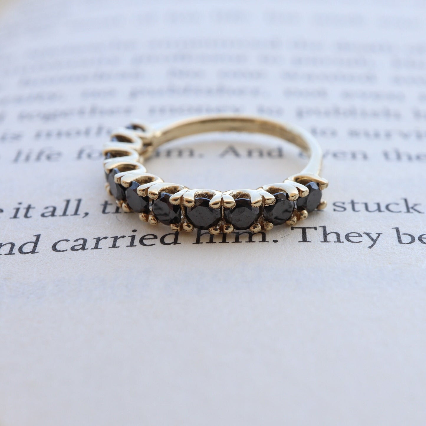 Gold ring with black diamonds displayed on an open book.