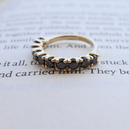 Gold ring with black diamonds displayed on an open book.