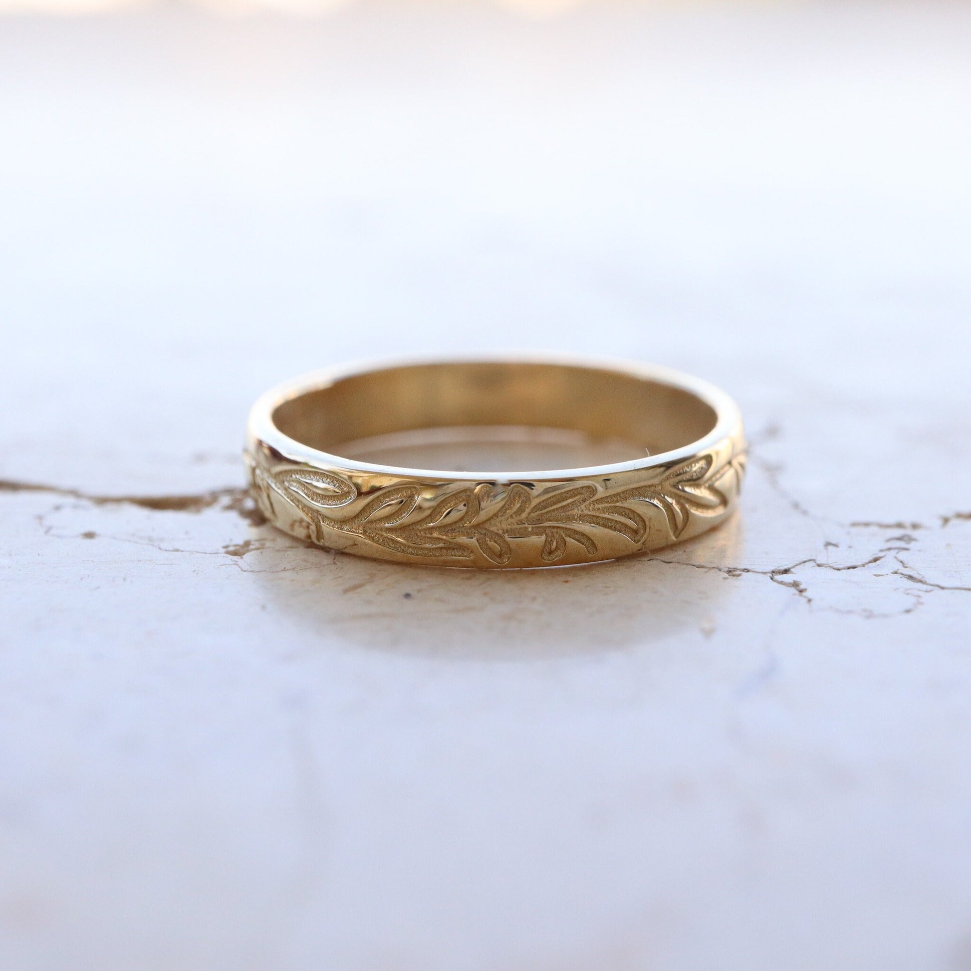 Elegant Gold Leaf Wedding Band displayed on a marble slab